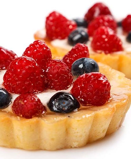 Sweet cakes with berries on white background